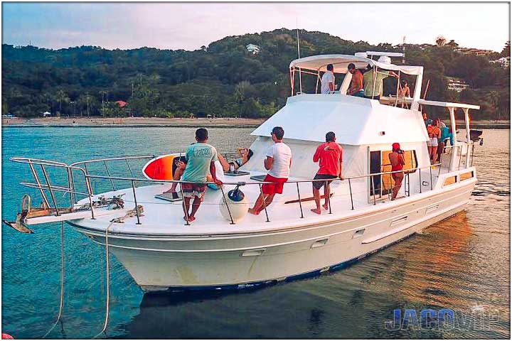 party boat anchored with guests at sunset