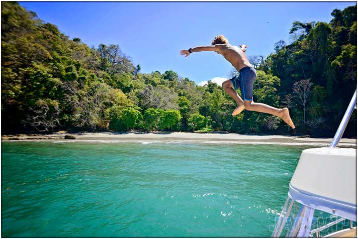 Guy jumping off boat near private beach