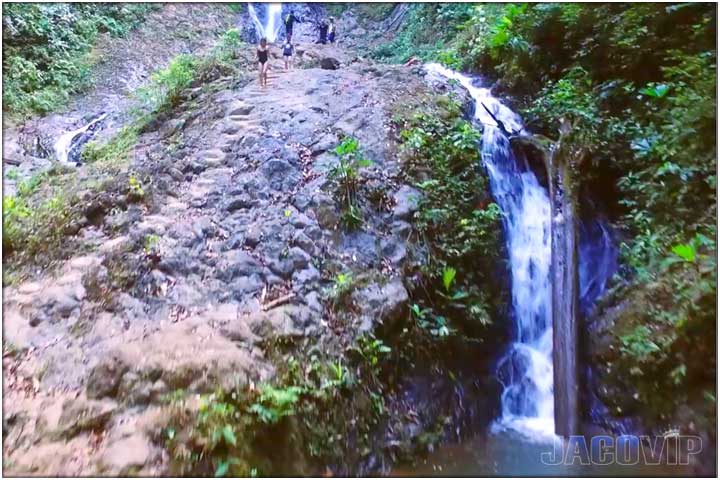 People walking along rocks to waterfall