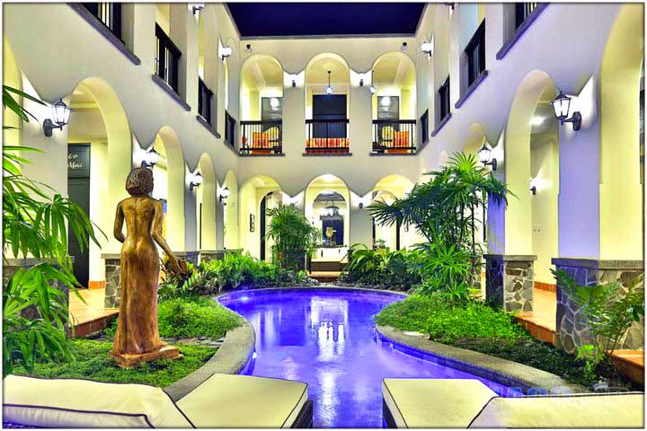 View of swimming pool in courtyard with lounge chairs and statue of a woman