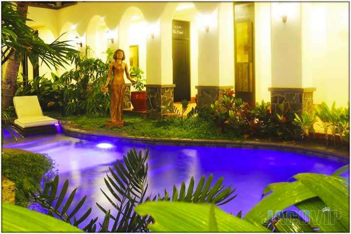 Swimming pool with statue of woman and lit arch ways