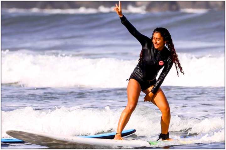 Girl in black swimsuit learning to surf