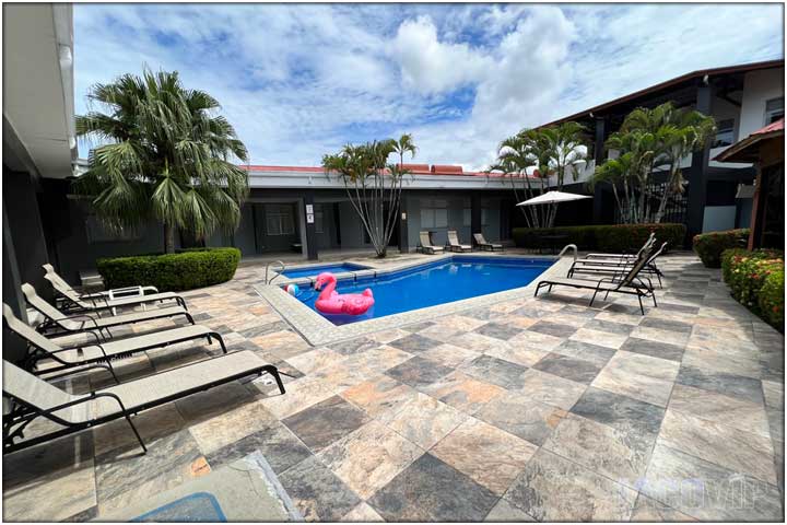 Back of lounge chairs with view of pool and both buildings