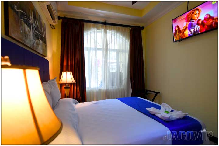 Queen size bed with white sheets and blue runner at foot of bed