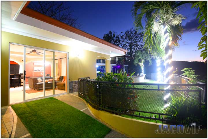 View of entrance at night with lights wrapped around palm trees